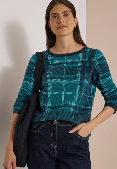 Langarm Pullover mit Karomuster deep petrol blue Frau in kariertem Türkis-Pullover und Jeans, lässige Schultertasche, Hand in Tasche.