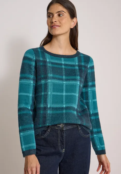Langarm Pullover mit Karomuster deep petrol blue Frau trägt langärmligen Pullover mit türkis-blauem Karomuster und Jeans.