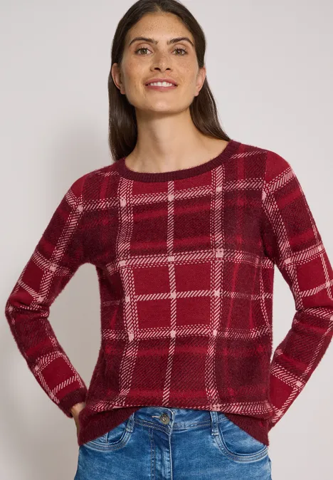 Langarm Pullover mit Karomuster red wine Frau mit rotem kariertem Pullover und Jeans, die lächelnd Hände in den Taschen zeigt.