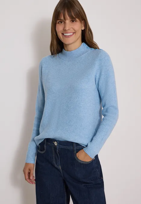 Pullover mit Struktur und Knopfdetail easy blue melange Fröhliche Frau in hellblauem Pullover und dunklen Jeans vor neutralem Hintergrund.