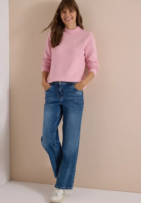 Pullover mit Struktur und Knopfdetail mellow rose melange Frau trägt rosa Pullover, blaue Jeans und weiße Sneaker vor beigefarbenem Hintergrund.
