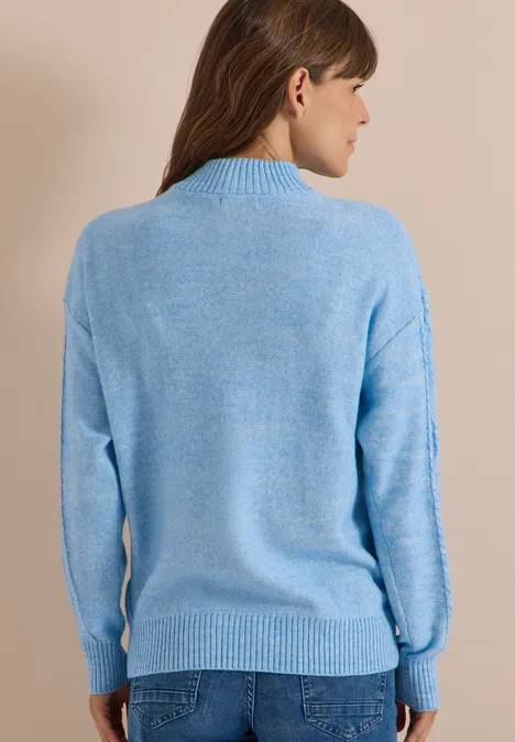 Frau von hinten in hellblauem Pullover und Jeans.