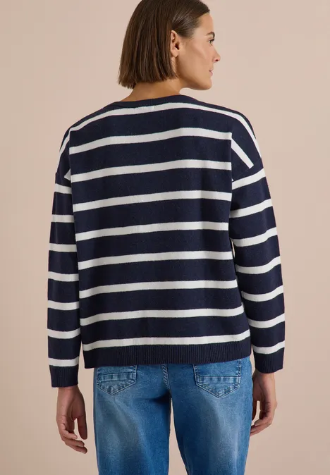 Eine Frau von hinten in blau-weiß gestreiftem Pullover und Jeans.