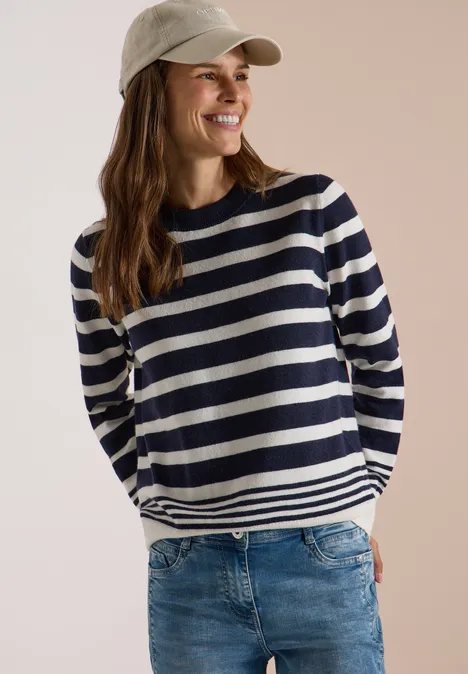 Pullover mit Rundhals und Streifen urban dark blue melange Eine lächelnde Frau mit gestreiftem Pullover, Jeans und Baseballcap vor neutralem Hintergrund.