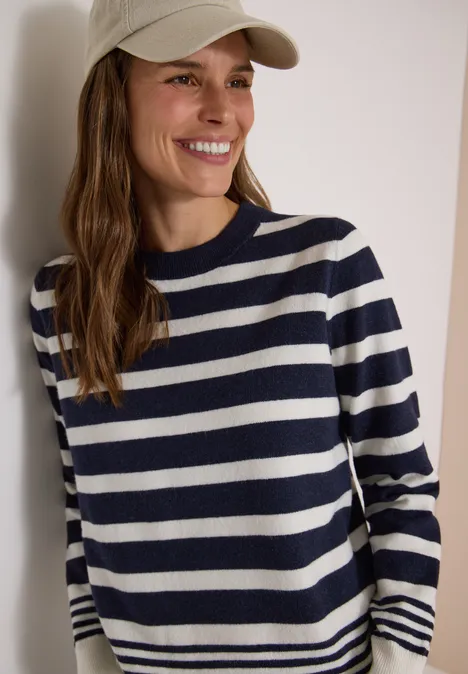 Pullover mit Rundhals und Streifen urban dark blue melange Lächelnde Frau in marine-weiß gestreiftem Pullover und beigefarbener Baseballmütze vor hellem Hintergrund.