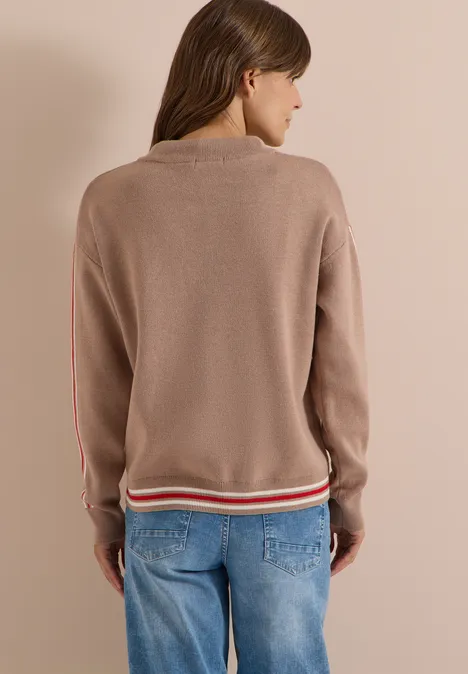 Trui met col en college-details creamy mocha melange Vrouw van achteren met taupekleurige trui met rood-witte zoom en blauwe spijkerbroek.