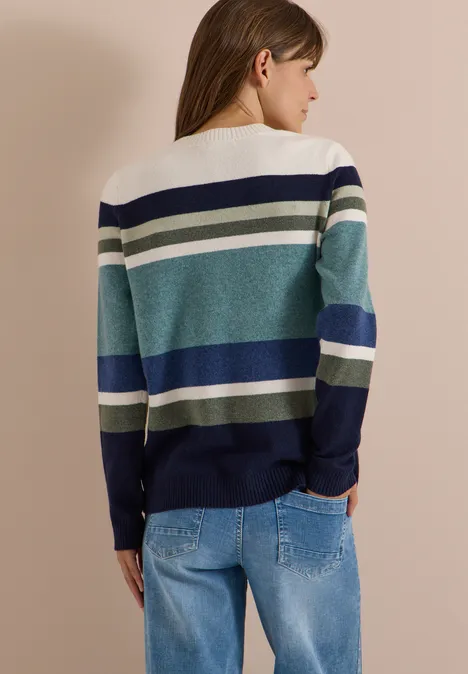 Sweter z okrągłym dekoltem i w paski mineral blue melange Kobieta widziana od tyłu w pasiastym swetrze w kremowym, turkusowym i niebieskim odcieniu oraz jasnych dżinsach.