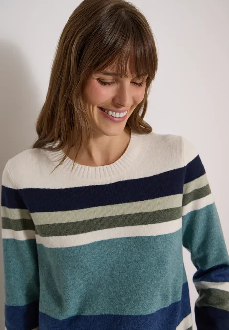 Sweter z okrągłym dekoltem i w paski mineral blue melange Uśmiechnięta kobieta w pasiastym swetrze w niebiesko-zielono-kremowych odcieniach na jasnym tle.