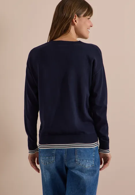 Pullover mit Rundhals und Layering-Detail urban dark blue Frau von hinten in dunkelblauem Pullover mit weißen Streifen an Bündchen und blauen Jeans.