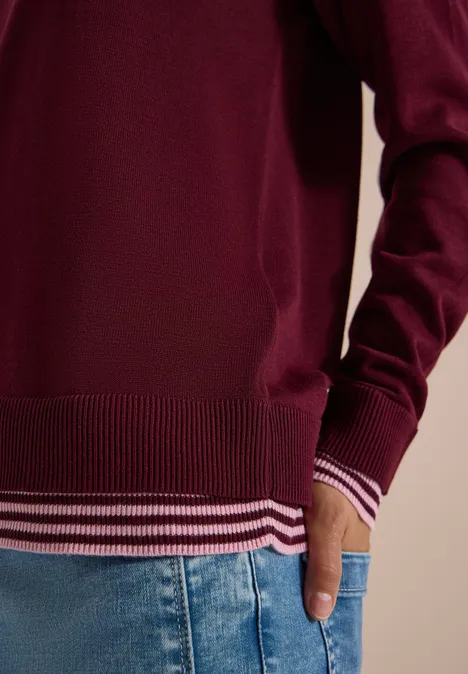 Pullover mit Rundhals und Layering-Detail red wine Roter Pullover mit gestreiftem Saum und Jeans, rechte Hand in der Hosentasche.