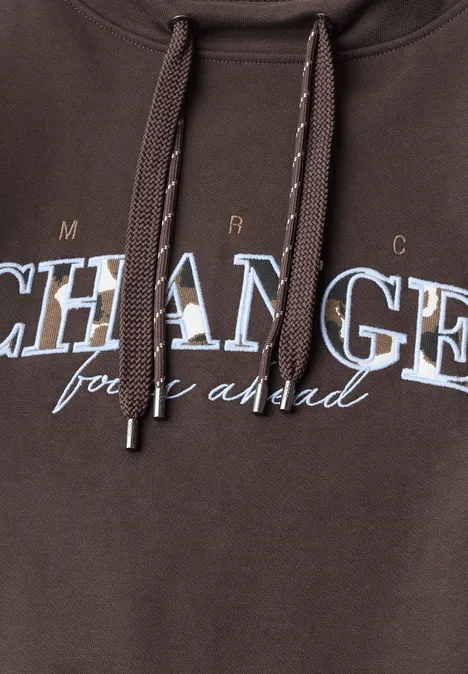Brauner Kapuzenpullover mit Kordelzug und weiß-blauem Schriftzug 'CHANGE for a good'.