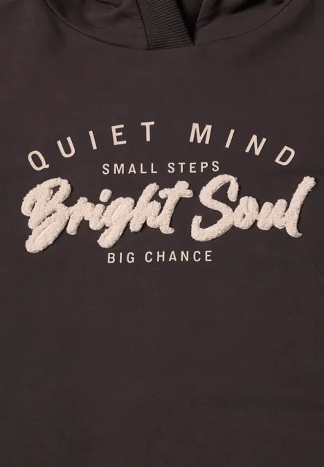 Dunkles Shirt mit weißem Aufdruck: ‚Quiet Mind, Small Steps, Bright Soul, Big Chance‘.