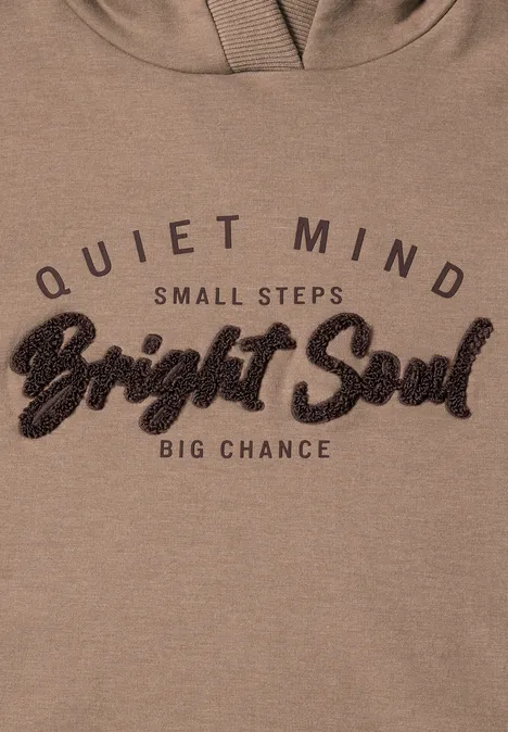 Sweat à capuche beige avec l'inscription 'Quiet Mind, Small Steps, Bright Soul, Big Chance'.