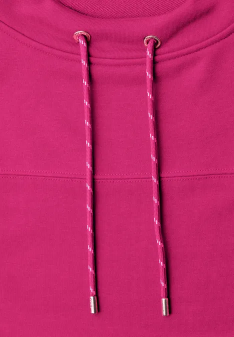 Close-up van een roze hoodie met tweekleurige aantrekkoorden en zilverkleurige uiteinden.