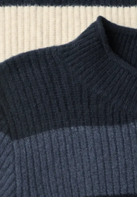 Nahaufnahme eines gerippten Pullovers in Creme-, Dunkel- und Mittelblau.