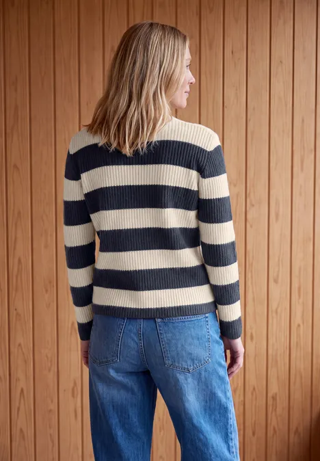 Pullover mit Turtle Neck und Streifen urban dark blue Frau von hinten in blau-beigem gestreiftem Pullover und Jeans vor Holzvertäfelung.
