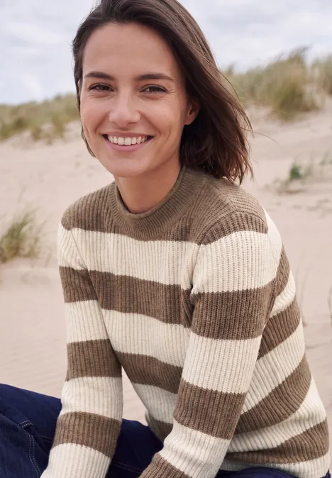 Pullover mit Turtle Neck und Streifen creamy mocha melange Eine lächelnde Frau in gestreiftem Pullover an einem Sandstrand.