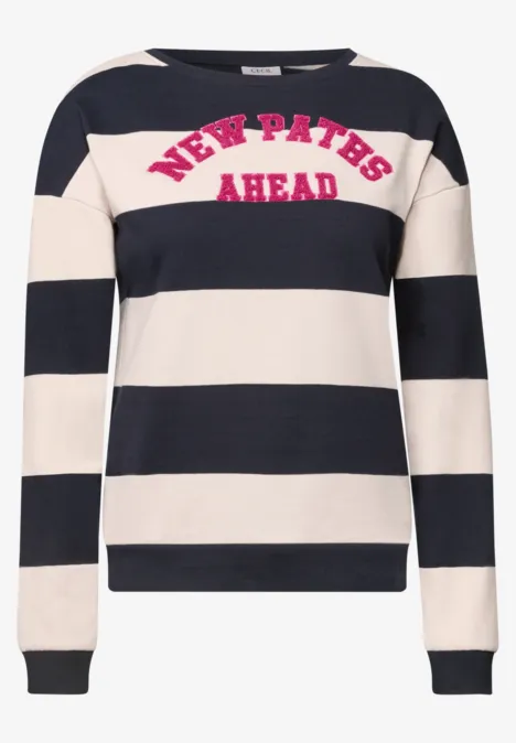Weiß-schwarz gestreifter Pullover mit pinkem Schriftzug 'NEW PATHS AHEAD' auf der Brust.