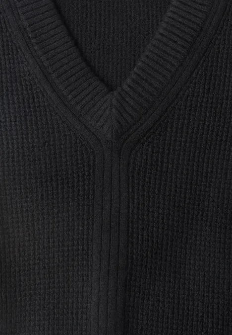 Pull sans manches uni à col en V Black Nahaufnahme eines schwarzen, V-förmigen Strickpullovers mit sichtbarer Struktur.