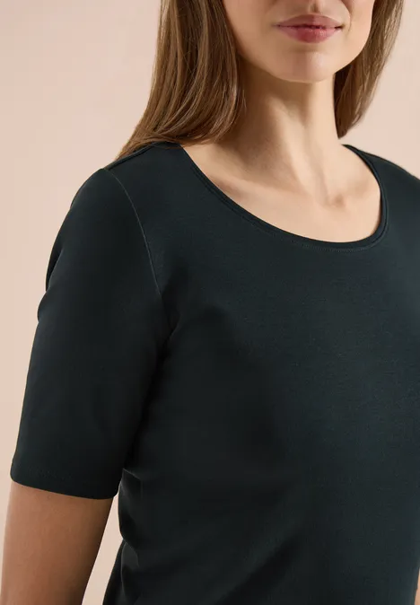 Vrouw draagt eenvoudig zwart T-shirt met korte mouwen en ronde hals.