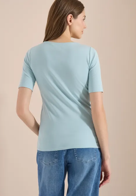 Femme de dos portant un t-shirt bleu clair et un jean.