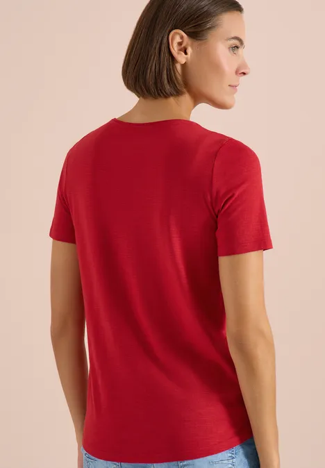 Frau von hinten in rotem T-Shirt, schlicht vor neutralem Hintergrund