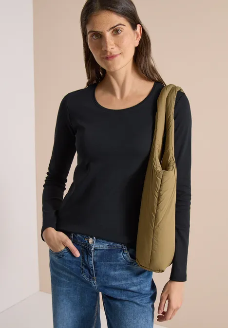 Basic shirt met lange mouwen en ronde hals Black Eine Frau mit schwarzem Langarmshirt, blauen Jeans und olivgrüner Umhängetasche lächelnd