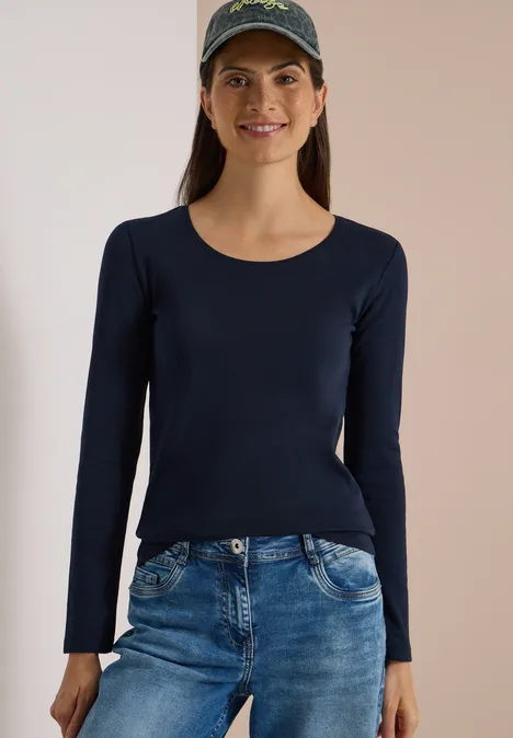 Basic Langarm Shirt mit Rundhals universal blue Junge Frau in dunkelblauem Langarmshirt, Jeans und Baseballcap lächelt freundlich.