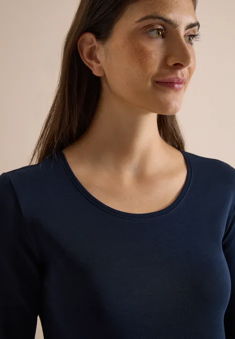 Basic Langarm Shirt mit Rundhals universal blue Eine junge Frau mit braunen Haaren trägt ein dunkelblaues Langarmshirt und blickt seitlich.