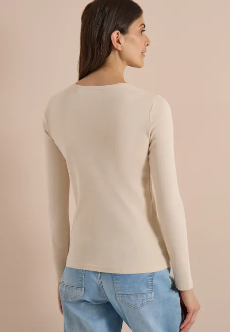 Basic shirt met lange mouwen en ronde hals pearl beige Rückansicht einer Frau in beigem Langarmshirt und blauer Jeans vor neutralem Hintergrund.