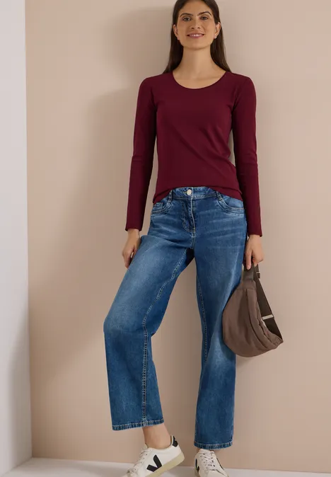 Basic Langarm Shirt mit Rundhals red wine Frau in Bordeaux-Langarmshirt, weitem Jeans, weißen Plateausneakern und brauner Handtasche vor beigem Hintergrund.