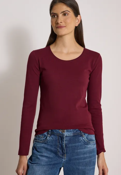 Basic Langarm Shirt mit Rundhals red wine Junge Frau in bordeauxfarbenem Langarmshirt und Jeans vor neutralem Hintergrund.