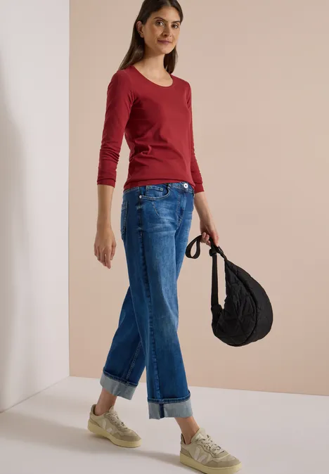 Basic Langarm Shirt mit Rundhals russet red Junge Frau in rotem 3/4-Arm-Shirt, weiten, umgeschlagenen Jeans und beigen Sneakern, mit schwarzer Tasche.