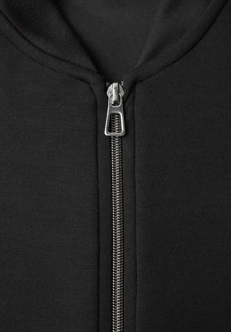 Gros plan d’une fermeture éclair métallique sur un sweat à capuche noir.