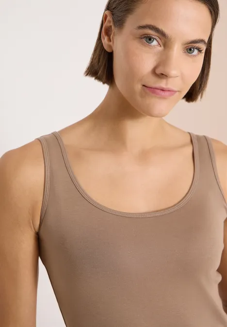 Femme portant un débardeur taupe sur fond blanc.