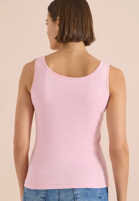 Rückansicht einer Frau, die ein ärmelloses rosa Top trägt.