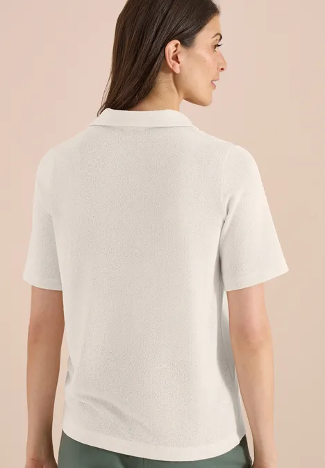Effen polo met korte mouwen macadamia beige Rugaanzicht van een vrouw in een eenvoudig, crèmekleurig poloshirt met korte mouwen.