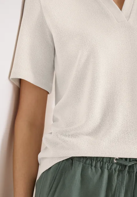 Effen polo met korte mouwen macadamia beige Iemand draagt een lichtbeige T-shirt met korte mouwen en V-hals en een donkergroene losse broek met koord.