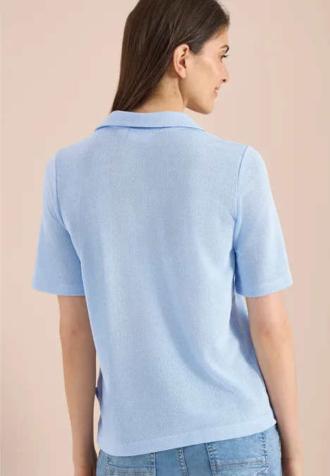 Effen polo met korte mouwen fresh water blue Vrouw van achteren in lichtblauw poloshirt met korte mouwen en blauwe jeans voor een beige achtergrond.