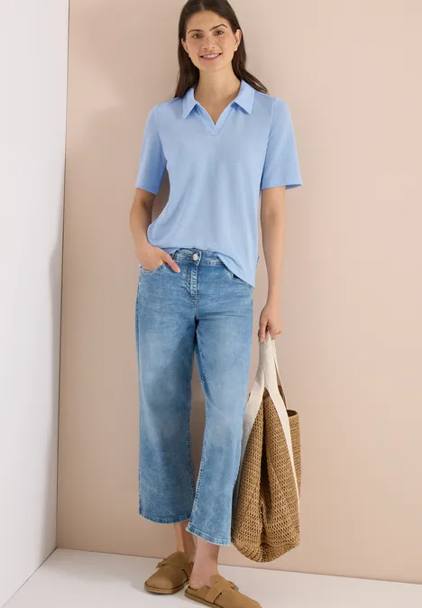 Effen polo met korte mouwen fresh water blue Vrouw in lichtblauw poloshirt, wijd korte jeans, stroentas en platte schoenen.