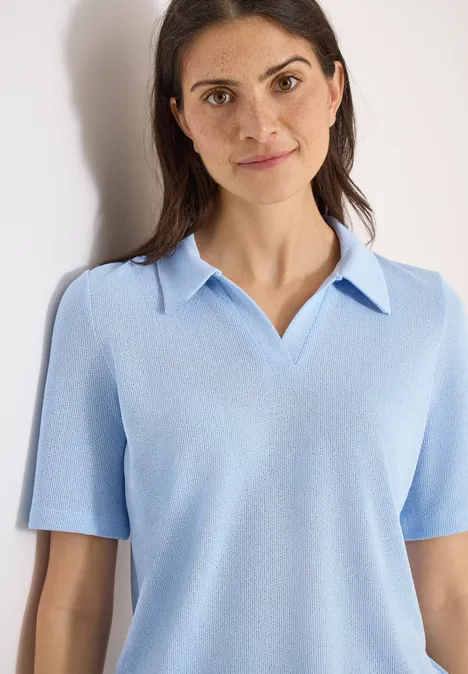 Effen polo met korte mouwen fresh water blue Vrouw in lichtblauw polohemd met korte mouwen voor een effen, lichte achtergrond.