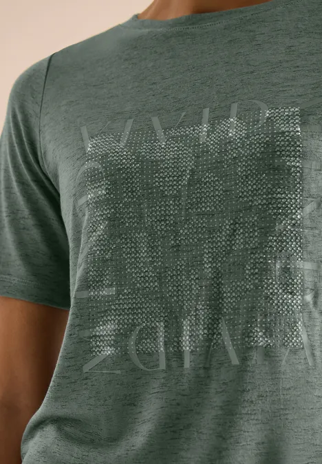 Grünes T-Shirt mit feiner Struktur und dezentem, quadratischem Print vorne.