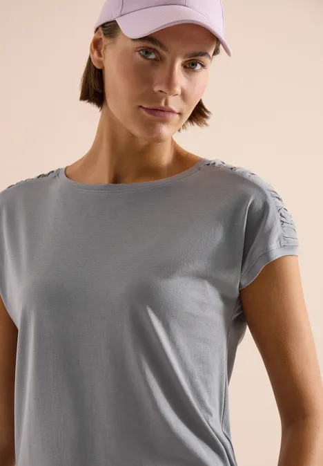 Shirt met korte mouwen en rimpels graphite light grey Opname van bovenlichaam met lichtblauw shirt en roze pet voor een neutrale, lichte achtergrond.