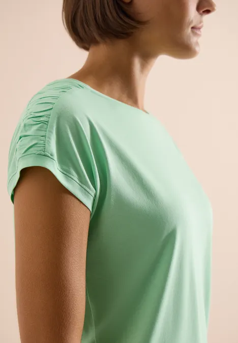 Shirt met korte mouwen en rimpels juicy lime Vrouw in mintgroen T-shirt met geplooide mouwen, opzij gefotografeerd.