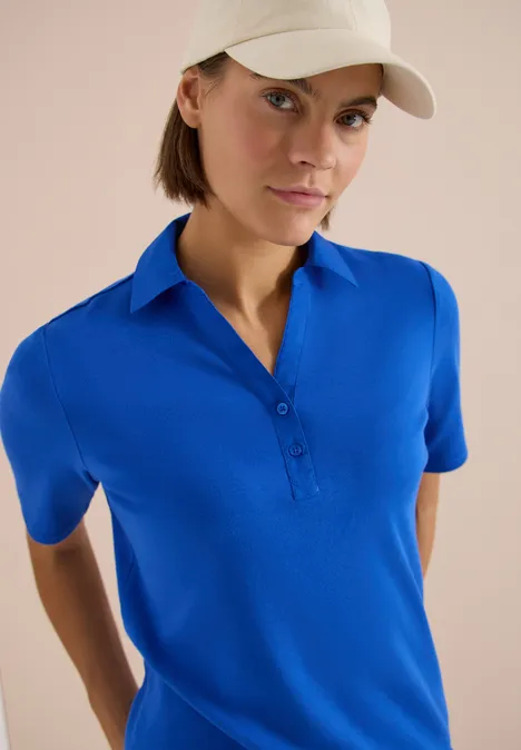 Basic Poloshirt mit Kurzarm surf blue Person trägt blaues Poloshirt und beige Baseballkappe vor hellem Hintergrund.