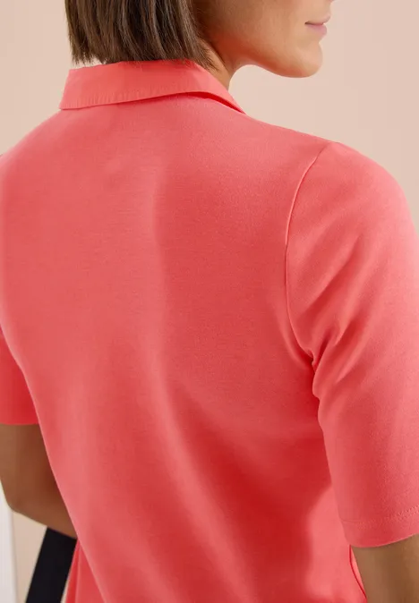Basic Poloshirt mit Kurzarm shiny coral Rückansicht einer Frau, die ein korallenfarbenes Poloshirt trägt.