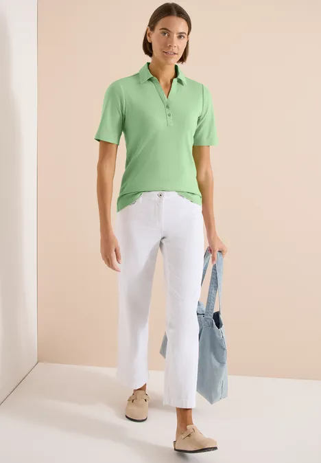 Basis polo met korte mouwen juicy lime Vrouw draagt groene polo, witte cropped jeans en comfortabele schoenen, met een blauwe tas.