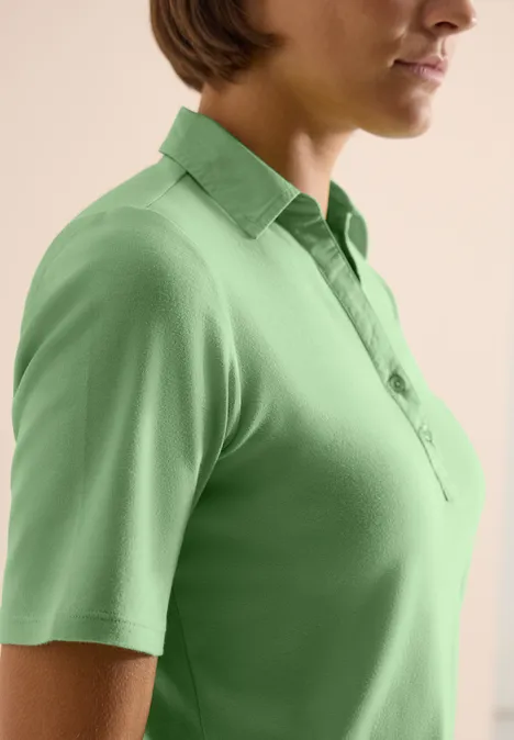 Basis polo met korte mouwen juicy lime Zijaanzicht van een vrouw in een lichtgroene polo