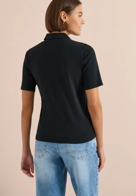 Basis polo met korte mouwen palm breeze green Achteraanzicht van een persoon in zwart poloshirt en blauwe jeans op neutrale achtergrond