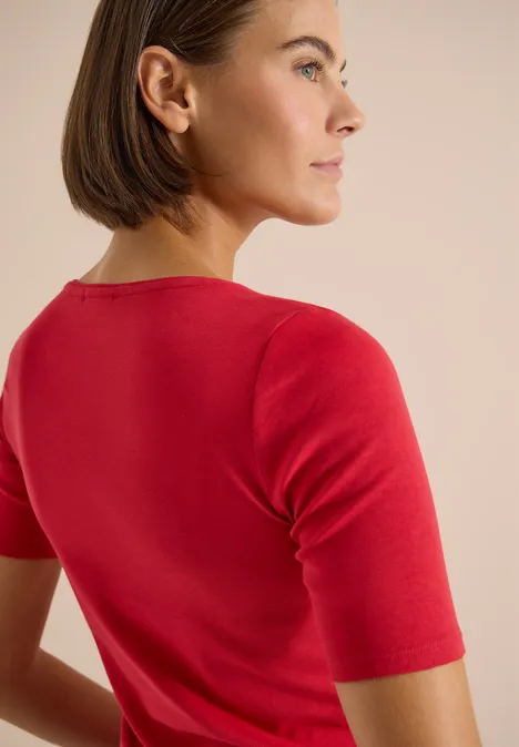 Basic T-Shirt aus Baumwolle tamarillo red Rückansicht einer Person in rotem Kurzarmshirt vor neutralem Hintergrund.